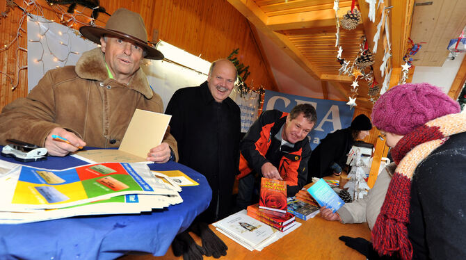 Buchverkauf zugunsten von »GEA-Leser helfen« auf dem Weihnachtsmarkt (von links): der gut behütete Gerhard Raff, GEA-Verleger Valdo Lehari jr. und Gunter Haug. GEA-FOTO: PACHER