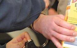 Ein Justizbeamter nimmt  dem Angeklagten im Landgericht Potsdam die Handschellen ab. Foto: Bernd Settnik 