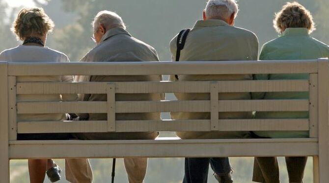 Rentner ruhen sich auf einer Parkbank auf. Foto: Ralf Hirschberger/Archiv