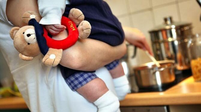 Betreuung zuhause: Eine Mutter kocht und hält dabei ihr Kleinkind auf dem Arm. Foto: Jan Woitas Betreuung zuhause: Eine Mutter kocht und hält dabei ihr Kleinkind auf dem Arm. Foto: Jan Woitas