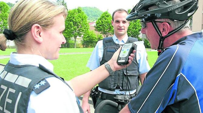 Die beiden Polizeibeamten Kai-Nils Reinhard und Isabell Volz bei der (gestellten) Überprüfung eines Fahrradfahrers. GEA-FOTO: DÖ