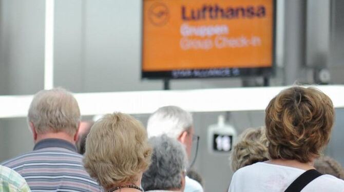 Reisende stehen in einer Schlange vor den Check-In-Schaltern der Lufthansa am Flughafen in München (Oberbayern). Foto: Andrea