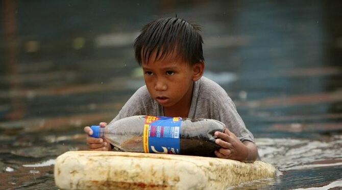 Das Ziel im Blick: Ein Junge watet durch eine überflutete Straße. Foto: Francis R. Malasig