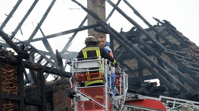 Ein Feuerwehrmann und ein Polizist suchen in den Trümmern des ausgebrannten Gebäudes nach Leichen. Foto: Uwe Zucchi