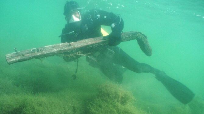 Ein Taucher birgt ein Wrackteil aus dem Bodensee. FOTO: dpa