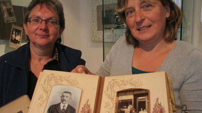 Ein Fotoalbum aus Amerika für die Daheimgebliebenen halten Beatrice Burst und Birgit Wallisser-Nuber (von links) in der Hand. Das Stück ist derzeit in der Ausstellung über historische Kameras im Gomaringer Schloss zu sehen. GEA-FOTO: WALDERICH