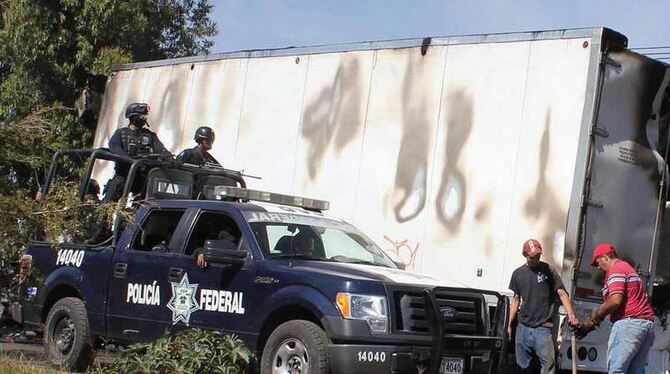 Ermittler durchsuchen bei Michoacan einen ausgebrannten Lastwagen. In dem Wrack wurden fünf Leichen entdeckt. Foto: epa/str