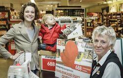 Die Berlinern Caroline Rosales (l) mit Söhnchen Maxime neben einer Verkäuferin an der Kasse eines Supermarktes in Berlin. Fot