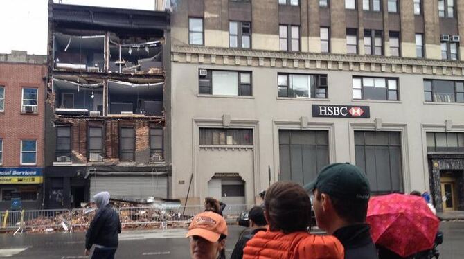 Passanten stehen vor einer eingestürzten Hausfassade in Lower Manhattan, New York. Wirbelsturm »Sandy« hat enorme Schäden ang