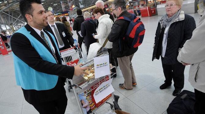 Ein Mitarbeiter des Köln Bonn Airport verteilt Süßigkeiten an wartende Passagiere. Foto: Henning Kaiser