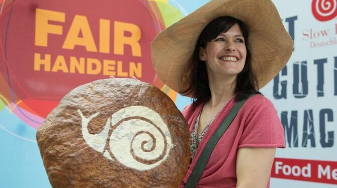 Modell Katrin hält während eines Fototermins ein Brot mit dem Logo der Organisation Slow Food in den Händen, im Hintergrund steh