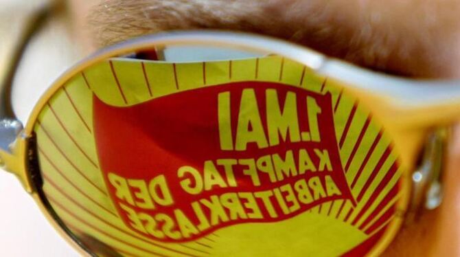 In der Sonnenbrille eines Mannes spiegelt sich ein Plakat mit der Aufschrift »1. Mai Kampftag der Arbeiterklasse«. Foto: Fran