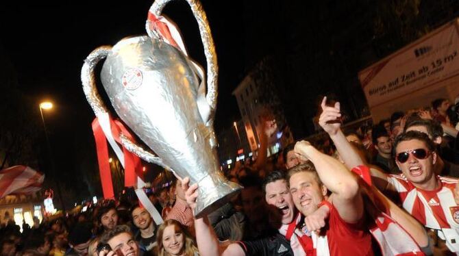 Fußballfans feiern in München mit einer Nachbildung des Champions League-Pokals. Foto: Tobias Hase