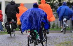 Radfahrer schützen sich mit Regenponchos vor den anhaltenden Niederschlägen. Foto: Jens Wolf