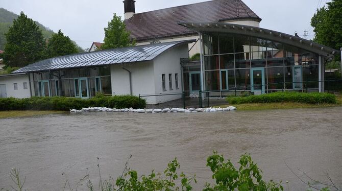 Das Gemeindehaus der katholischen Gemeinde Bruder Konrad in Unterhausen war am frühen Morgen von der Echaz überflutet worden. Die Feuerwehr baute einen Damm aus Sandsäcken und pumpte das Gebäude leer. FOTO: SCHÖBEL Das Gemeindehaus der katholischen Gemeinde Bruder Konrad in Unterhausen war am frühen Morgen von der Echaz überflutet worden. Die Feuerwehr baute einen Damm aus Sandsäcken und pumpte das Gebäude leer. FOTO: SCHÖBEL