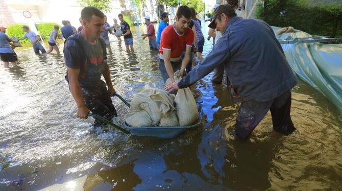 Helfer schichten Sandsäcke in einer überfluteten Straße in Magdeburg zu Dämmen auf. Foto: Jens Wolf