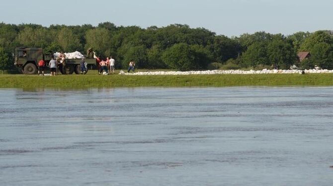 Freiwillige Helfer und Bundeswehrsoldaten stapeln Sandsäcke am Deich in Dömitz an der Elbe. Foto: Marcus Brandt