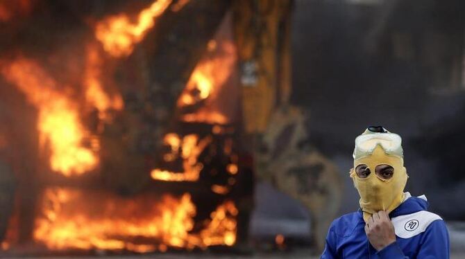Ein vermummter Demonstrant vor einer brennenden Barrikade auf dem Istanbuler Taksim-Platz. Foto: Tolga Bozoglu