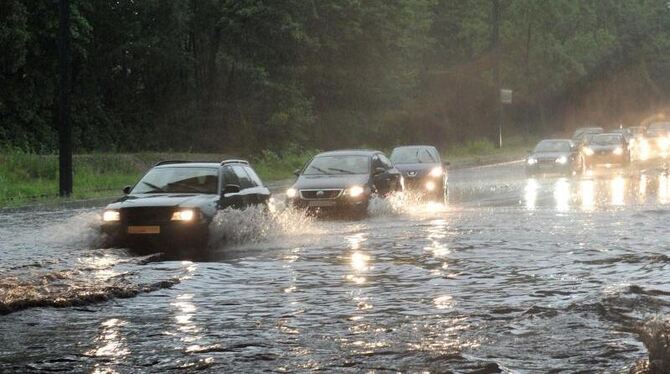 Autos fahren in Augsburg über eine überflutete Straße. Foto: Stefan Puchner