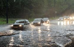Autos fahren in Augsburg über eine überflutete Straße. Foto: Stefan Puchner