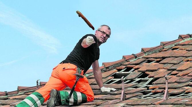 Manche Ziegel sind unrettbar vom Hagel zerschossen und fliegen in den Container. Hans-Martin Votteler vom Metzinger Bauhof bei d