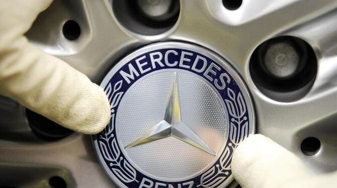 Ein Arbeiter drückt im Werk Sindelfingen ein Mercedes-Emblem auf ein Rad. Foto: Bernd Weißbrod