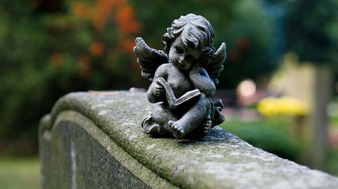 Ein Engel liegt auf einem Grabstein.