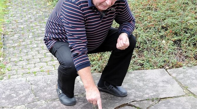 Im Pfalzgrafenweg zeigt Sigurd Brenner auf seine in jüngster Zeit abgesackten Steinplatten der Terrasse.