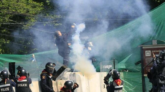 Polizisten schleudern eine Tränengasgranate in Richtung der Demonstranten. Foto: Narong Sangnak