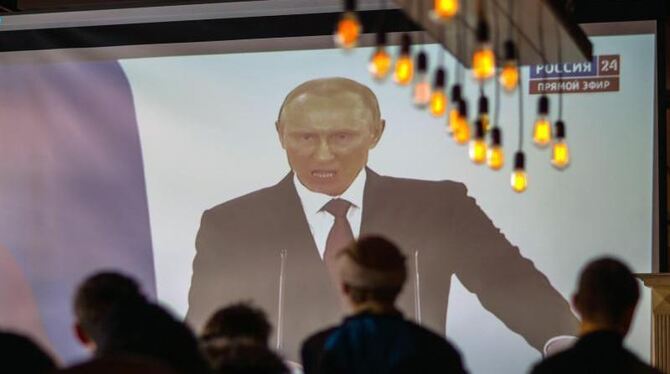 Menschen verfolgen in Simferopol auf einer Videoleinwand die Live-Übertragung der Rede von Putin. Foto: Hannibal