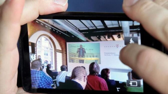 Ein Blogger überträgt eine Live-Videokonferenz mit seinem Handy. Foto: Markus Scholz/Illustration