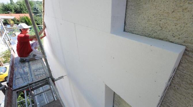 Ein Arbeiter befestigt eine Styroporplatte zur Wärmedämmung an einer Hausfassade. Foto: Armin Weigel/Archiv