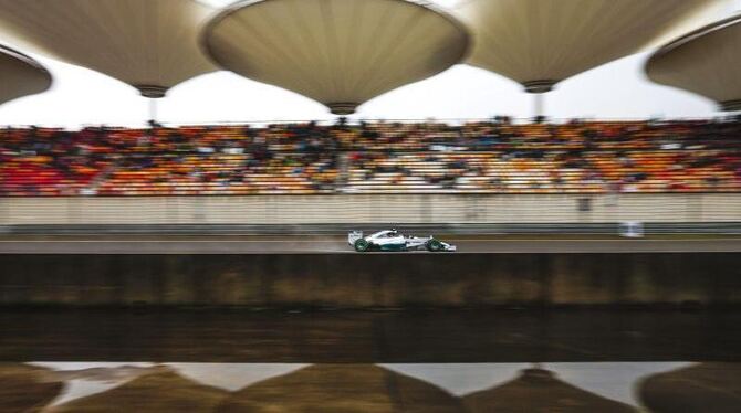 Nico Rosberg rast in Shanghai an den Tribünen vorbei, deren markante Dächer sich im Wasser eines Bassins spiegeln. Foto: Dieg