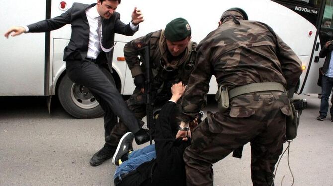 Erdogan-Berater Yusuf Yerkel holt zum Tritt aus, während zwei Sicherheitskräfte einen Mann am Boden festhalten.