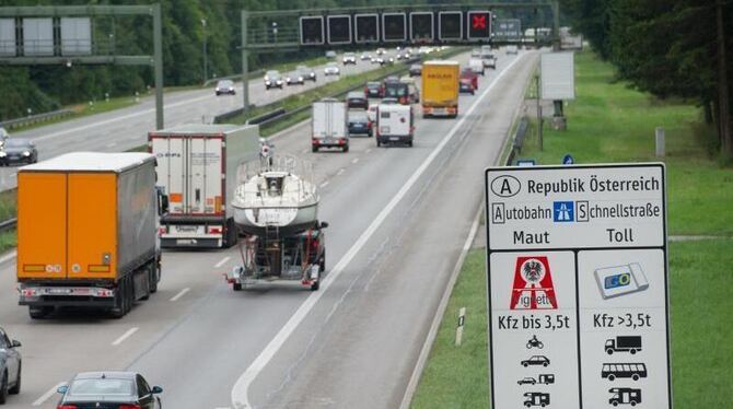 Autos und Lkws fahren auf der Autobahn A8 bei Holzkirchen an einem Hinweisschild zur Mautpflicht in Österreich vorbei. Foto: