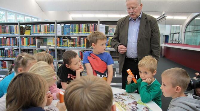 Dieter Schmidt, Vorsitzender des Mössinger Bücherei-Fördervereins, übergibt Tiptoi-Bücher und -Stifte an die Bücherei. Eine Grup