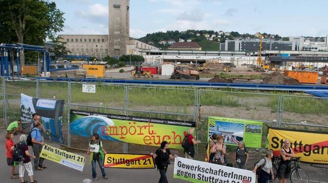 Vorne ein paar Demonstranten, hinter dem Zaun die Baustelle von Stuttgart 21.