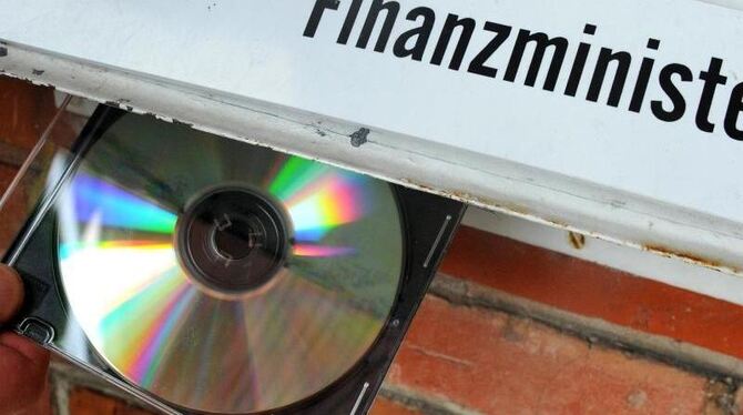 Eine CD wird symbolisch an den Briefkasten eines Finanzministeriums gehalten. Das US-Abkommen zu Steuersündern steht in der K