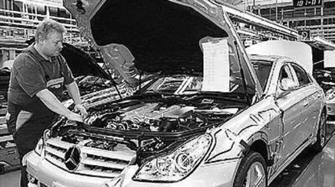 Ein Daimler-Chrysler-Mitarbeiter arbeitet am Motor eines Mercedes-Benz CLS. 
FOTO: DPA