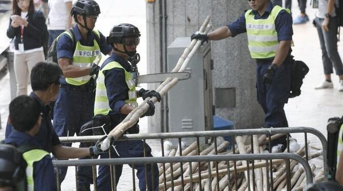 Polizisten beim Abbau von Bambus-Barrikaden im Zentrum von Hongkong. Foto: Rolex Dela Pena