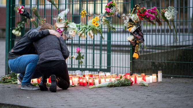 Ein Ehepaar trauert vor den abgelegten Kerzen und Blumen vor der Käthe-Kollwitz-Gesamtschule in Lünen, wo ein Schüler erstochen
