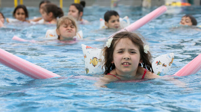 Erst mit Poolnudeln und Schwimmflügeln, dann ohne diese Hilfen: Die DLRG bringt Grundschulkindern das Schwimmen bei.  FOTO: DPA