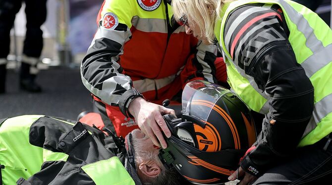 Sanitäter demonstrieren in einer gestellten Situation bei einem verletzten Motorradfahrer das Abnehmen des Helmes.
