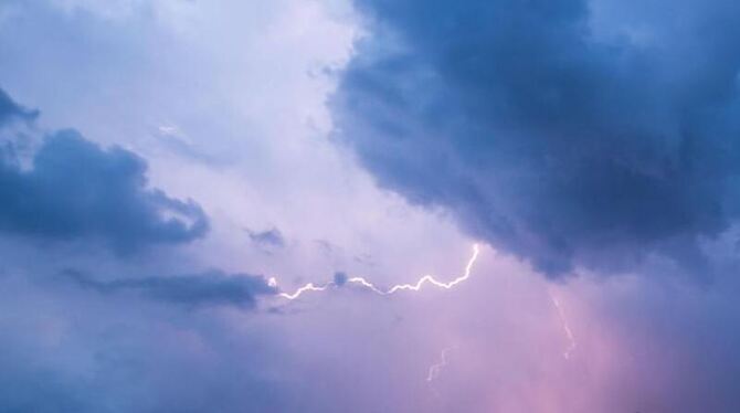 Blitz leuchtet zwischen den Wolken am Himmel