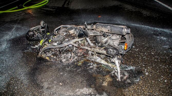 Das Wrack des verunglückten Motorrads liegt ausgebrannt auf der Bundesstraße