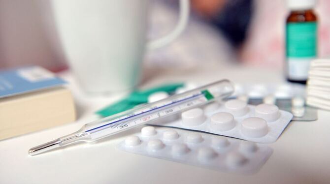 ARCHIV - ILLUSTRATION - 29.07.2016, Berlin: Medikamente und ein Fiberthermometer liegen auf einem Nachttisch.