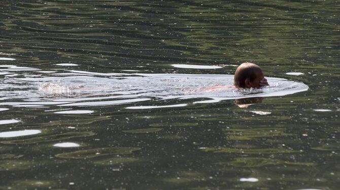 Ein Mann schwimmt in einem Baggersee