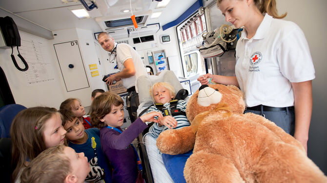 Teddy-Klinik ganz mobil: Kinder des Kinderhauses Mühlenviertel helfen im Krankenwagen vor dem Rathaus mit. FOTO: TRINKHAUS