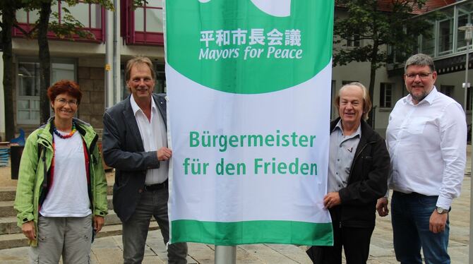 Karin Berkemer, Werner Schulz, Reinhard Glatzel und OB Ulrich Fiedler hissen vor dem Metzinger Rathaus die Friedensflagge von "M