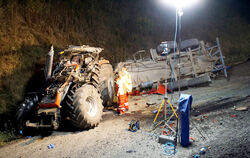 Rettungskräfte stehen neben einem verunfallten Traktor und einem doppelachsigen Anhänger an der Autobahn 8 (A8). Ein Traktorfahr
